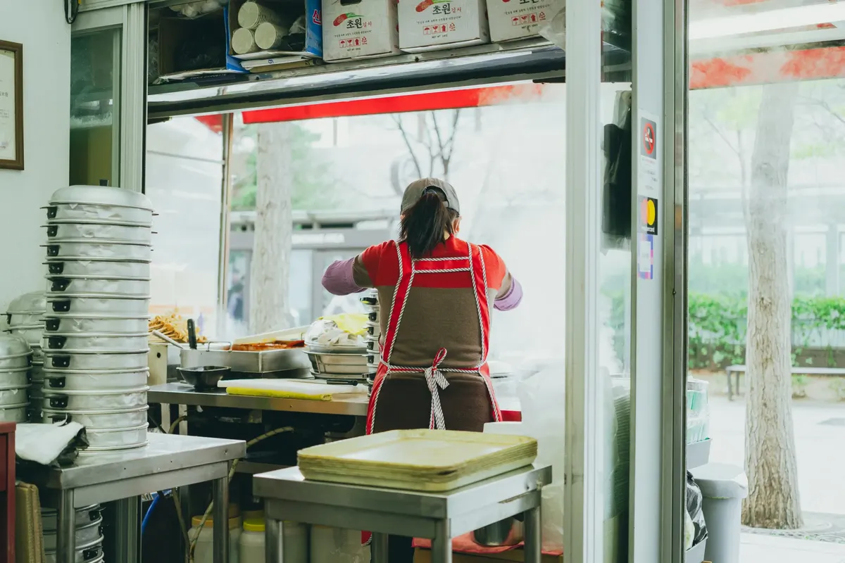 A street food vendor preparing dishes in a bustling Seoul, capturing Korean street cuisine.