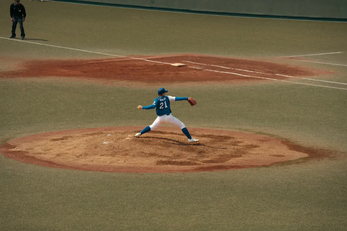 Baseball player mid-throw during a game at a Tokyo baseball field. Capturing the intensity and focus of sports.