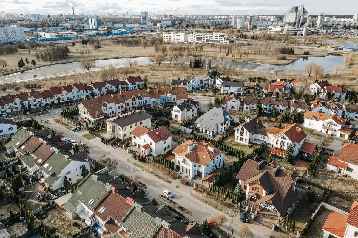Aerial photography capturing a vibrant suburban neighborhood with distinct red-roofed houses and surrounding greenery.