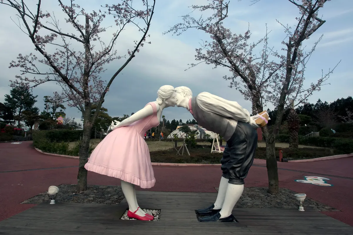 愛のランドパークにあり、サクランボの木々に囲まれた夫婦がキスしている彫刻